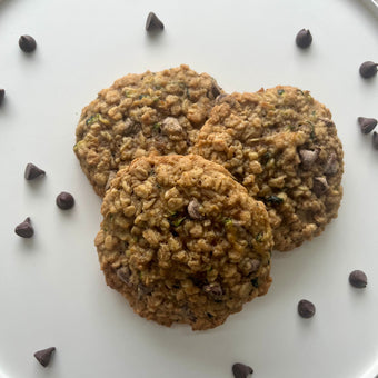 Three oatmeal cookies with chocolate chips on a white plate.
